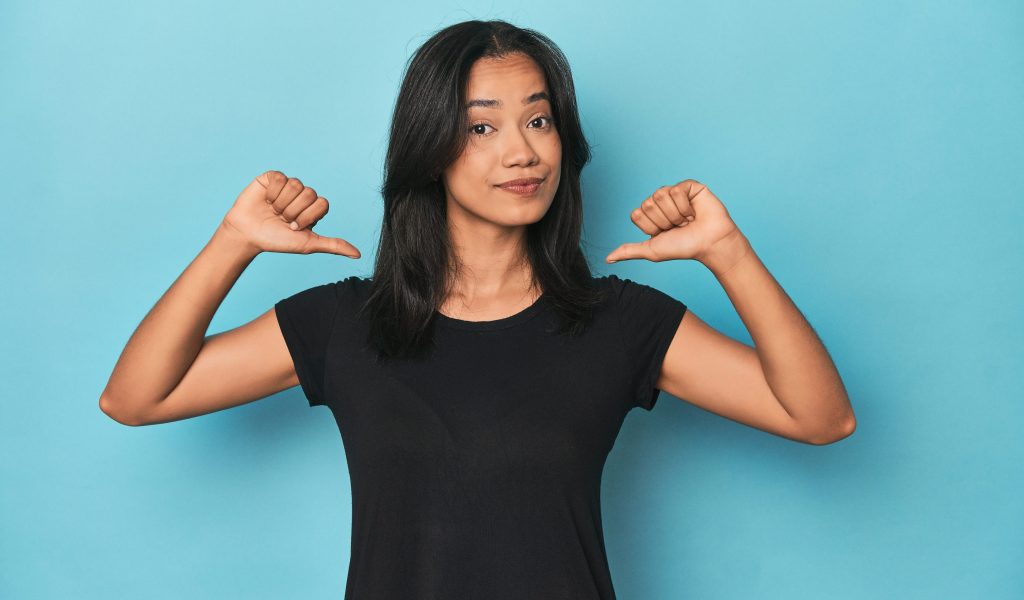 feels proud and self confident, example to follow. Filipina young woman on blue studio feels proud and self confident, example to follow.
